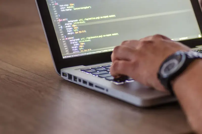 Dłoń pisze kod CSS, optymalizując pliki do wersji min.